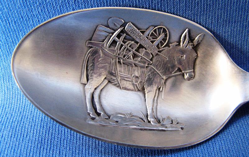 Elkton - Mary McKinney Mines Cripple Creek Colorado Bowl Closeup.JPG - SOUVENIR MINING SPOON ELKTON & MARY MCKINNEY MINES CRIPPLE CREEK COLORADO - Sterling silver souvenir mining spoon, embossed donkey loaded up with mining equipment in bowl, donkey carries sign that says “I helped built P.P.RR” (Pikes Peak Railroad), handle depicts scenes of the Elkton and Mary McKinney Mines in Cripple Creek, Colorado, also features a gold pan and pick and shovel, reverse features a windlass and mine bucket marked mine and shaft, reverse marked Sterling with rare maker mark E.L.D. for Eugene L. Deacon Jewelry Co. of Denver, CO maker of Sterling spoons from 1900 to 1912, 5 1/8 in. long [Elkton Mine - Located in Cripple Creek, Colorado, Elkton came to life in 1891 after a blacksmith from Colorado Springs named William Shemwell staked a claim in the Cripple Creek area. The town sprung up around the mine to support the miners and their families. By 1892, the mine still had not produced results and Shemwell decided to sell the claim to three brothers: George, Douglas and Sam Bernard.  By 1894, the Bernard brothers had also been unsuccessful and gave the mine only two weeks before they would consolidate their loses. Near the end of these two weeks, a vein of gold was discovered which produced $40,000 within a week. The mine had finally become a success.  In 1899, a man by the name of Ed De LaVergne proposed to merge his mine located directly next to the Elkton with the Elkton. With this move, the Elkton mine became one of the largest mines in the Cripple Creek area. The mine would yield more than $16 million in gold and would be active until 1956. Several of the men involved, including Ed De LaVergne and the Bernards, became millionaires, but most of them were dead broke again by the time of their deaths.  The town itself was never actually platted, but the area simply became known as Elkton, Colorado. It had its own post office for a while and grew to reach a population of 2900 people at its peak.  Mary McKinney Mine - The Mary McKinney Mine was founded in May of 1891. An unusual feature of the mine was the large cribbing wall that was built to prevent the mine’s dump rock from falling onto the railroad bed.  The Mary McKinney Mine which was located in Squaw Gulch in the Cripple Creek Gold Mining District was started by Frank Castello and the Houghton brothers.  Banker and mining baron David H. Moffat heavily bought into the property and by 1894 the owners were able to turn the property into one of the most productive in the gold mining district. Mary McKinney Mine holdings comprised 144 acres on Raven and Gold Hills within the town of Anaconda.  . Founded in 1894, the town was sprawled along a half mile of Squaw Gulch, about halfway between Cripple Creek and Victor. Anaconda was a composite of three other mining camps: Squaw Gulch, Mound City and Barry.  Once a bustling town of over 1,000 persons, the town was supported mainly by the Mary McKinney Mine. During the winter of 1904, a fire started that pretty much annihilated the town.  Unlike the massive relief efforts that rebuilt nearby Victor and Cripple Creek after their fires, Anaconda was left to die a slow death. While the mines were still in operation after the fire, most residents simply moved away.  Anaconda’s population fell from 1,000 to 250 and continued a steady decline to today’s ghost town status. The mine eventually closed in 1953. Over its 62 year history the Mary McKinney Mine yielded more than eleven million dollars in gold.]  